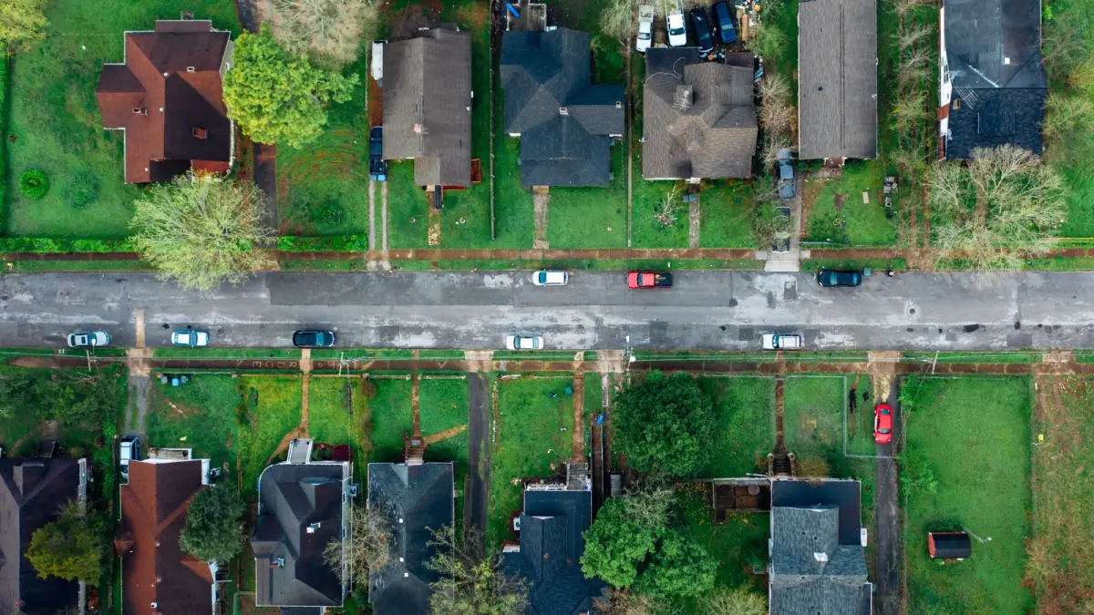 Aerial view of house roofs and gardens along a suburban street